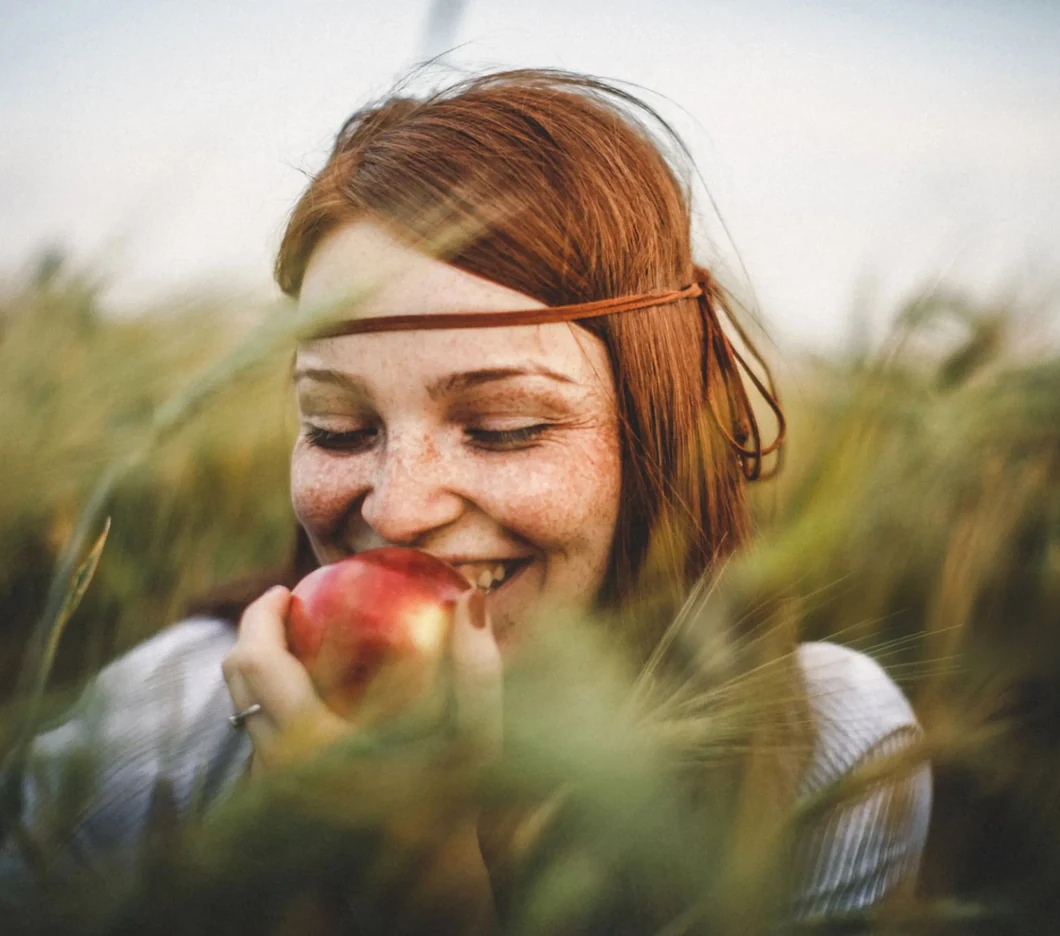 Een vrouw in het hoge gras eet een appel